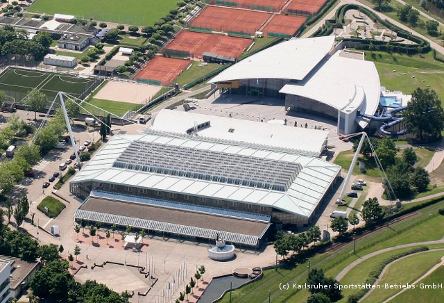 Das Bild zeigt ein großes Sportstadion mit verschiedenen Spielplätzen und Courts in der Nähe.