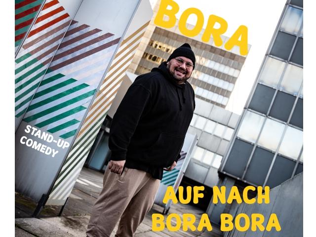 Ein Mann posiert für ein Werbefoto auf einer Steh Comedy-Show namens "BORA.".