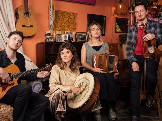 Eine Gruppe von Musikern, die verschiedene Instrumente wie Flöte, Gitarre und Geige spielten, versammelte sich auf einer Bühne beim Irish Folk Festival.