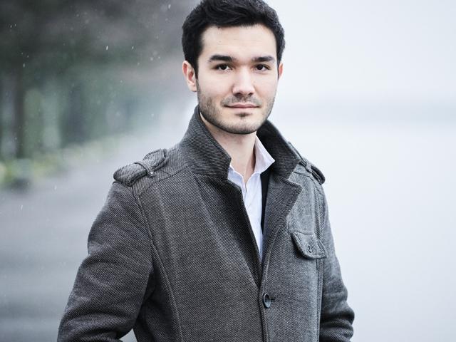 Ein Mann posiert für ein Foto mit offenem Mantel und regennassem, zerzaustem Haar.
