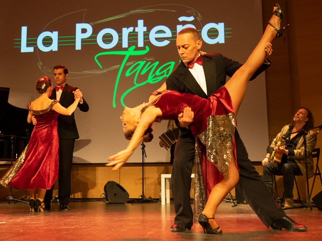 Eine Frau tanzt Tango, während ein anderer Mann ihr Bein stützt.