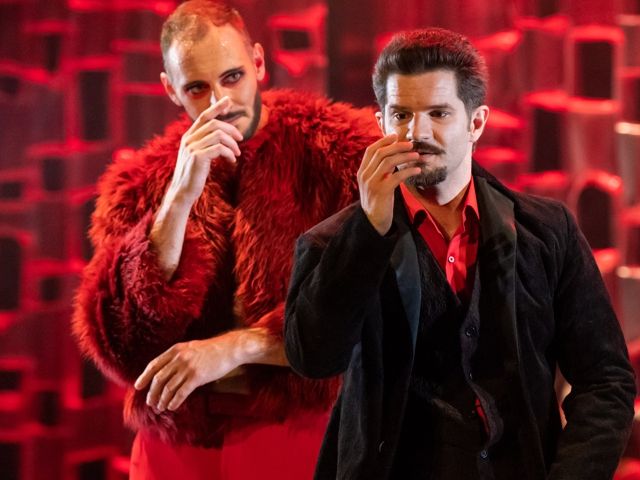 Zwei Männer auf der Bühne, einer in Rot und der andere in Schwarz, während einer Vorstellung.