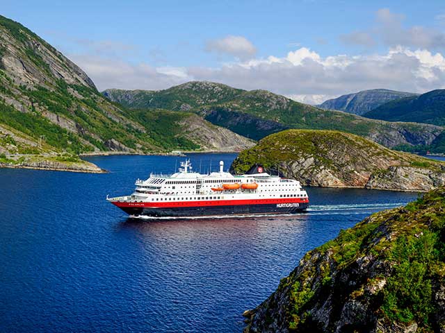 Großes rotes und weißes Fährschiff durchfährt den Fjord.
