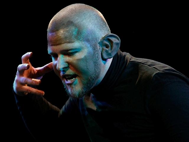 Ein Mann, der auf der Bühne performs und möglicherweise singt oder spricht.