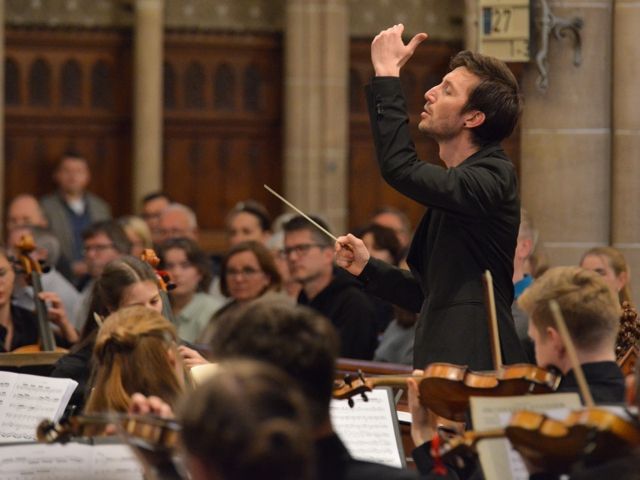 Ein Mann leitet ein Orchester bei einem Konzert.