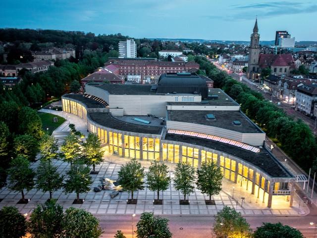 Ein großes modernes Gebäude bei Nacht, möglicherweise ein Kultur- oder Gemeindezentrum, unter einem Dämmerhimmel