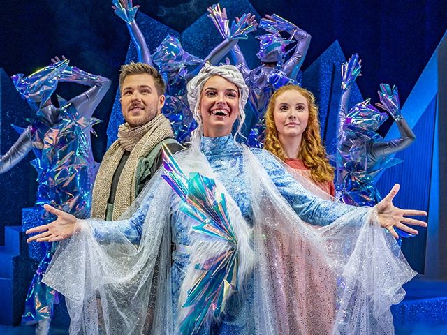 Drei Künstler posieren gemeinsam auf der Bühne, gekleidet als Eiskunstläufer und mit glitzernden Kostümen und Capes.