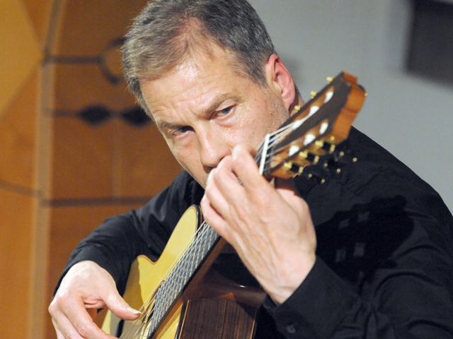Ein Mann spielt Gitarre auf der Bühne während eines Musikfestivals.